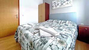 A bedroom with a bed, a wardrobe, a door, and a wall-mounted painting.