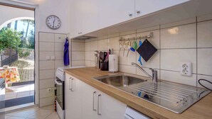 A modern kitchen with white cabinets, a stainless steel sink, and a wooden countertop.