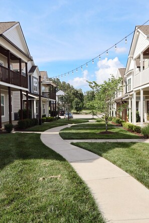 A residential street with houses, a curved sidewalk, and string lights.