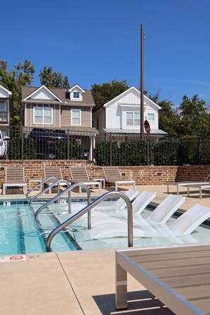 A swimming pool with lounge chairs and a stop sign in the background.