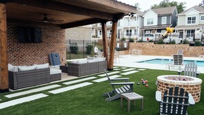 A backyard with a brick wall, a wooden pergola, a pool, and outdoor furniture. - Home on the East Side (Cookeville)
