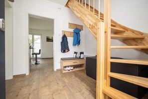 Cozy living space with a wooden staircase, bench, and coat rack.