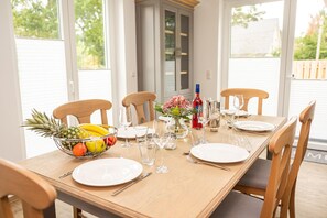 Enjoy a meal in this elegant dining area with a long table set for a special occasion, featuring a fruit bowl and fine wine.