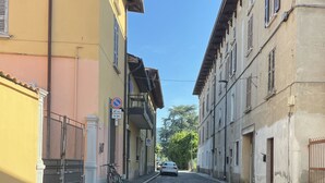 Una calle estrecha flanqueada por edificios, un automóvil estacionado y una bicicleta.