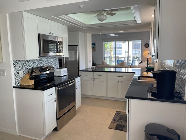 A modern kitchen with white cabinets, stainless steel appliances, and a black countertop.