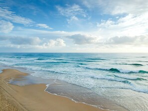 A beach with waves and a clear sky.