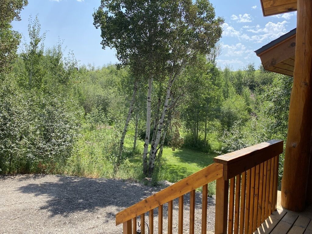 Una terraza de madera con un sendero de grava que conduce a un área boscosa.