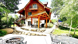 Une cabane en rondins dotée d’une véranda, d’un espace salon extérieur et d’un chemin en pierre.