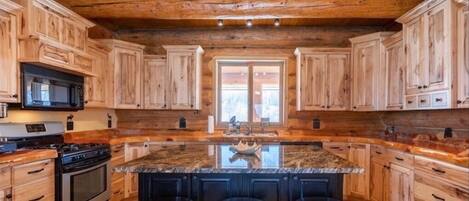 Una cocina amplia con armarios de madera, encimera de granito y una isla central con taburetes de bar.