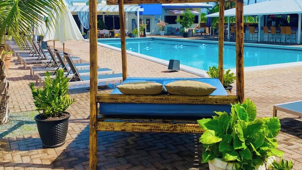 Ein Poolbereich mit einer Holz-Pergola, Liegestühlen und Topfpflanzen.