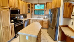 A modern kitchen with wooden cabinets, stainless steel appliances, and a large island. - Views, hot tub, spacious 3Bd, 3Ba w Tesla Charger (Robbinsville)