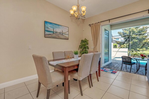 A dining area with a table, chairs, a chandelier, a painting, and a view of the outdoors. - Luxury Villa, Clubhouse, Pool, 15 mins from Disney (Davenport)
