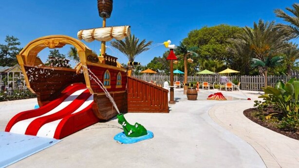 A pirate-themed play area with a ship-shaped slide, a green shark figure, and a fenced play zone. - Luxury Villa, Clubhouse, Pool, 15 mins from Disney (Davenport)