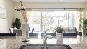 A modern kitchen with granite countertops, a stainless steel sink, and a hanging light fixture. - Luxury Villa, Clubhouse, Pool, 15 mins from Disney (Davenport)