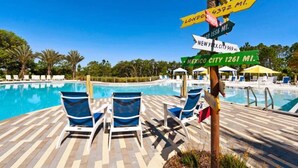 A poolside area with lounge chairs and a signpost indicating distances to various cities. - Luxury Villa, Clubhouse, Pool, 15 mins from Disney (Davenport)