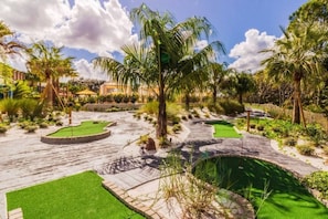 Ein Golfplatz mit Putting Green, Sandbunkern und Palmen.