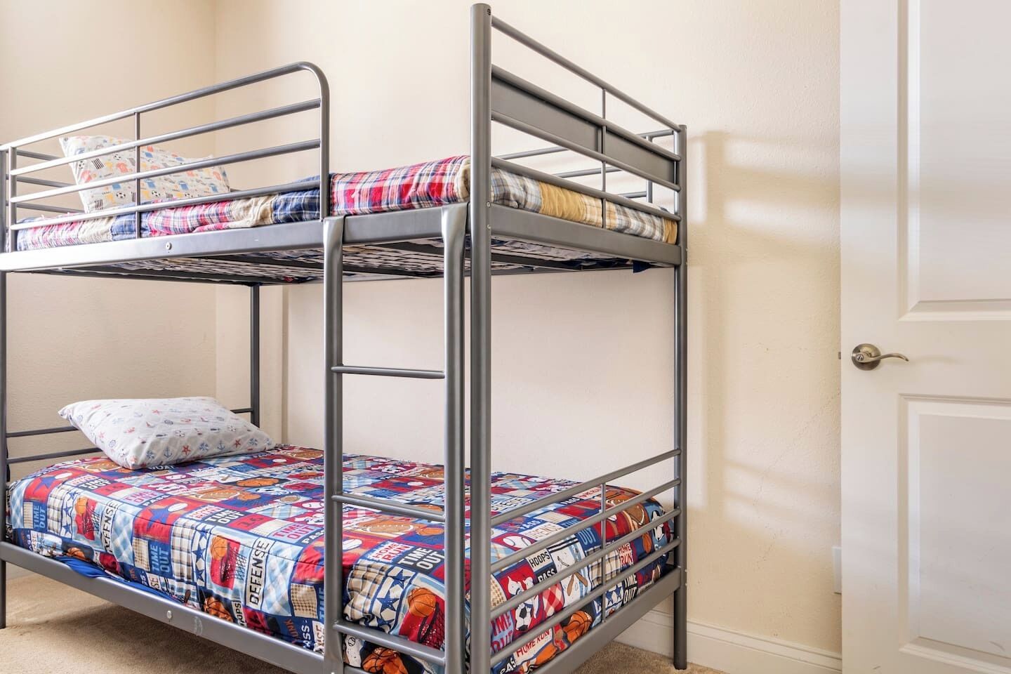 Een stapelbed met een bedspread met patroon, een kussen, en een deur op de achtergrond.
