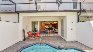 A residential property with a swimming pool, a dining area with red chairs, and a kitchen visible through an open doorway. - Luxury Villa, Clubhouse, Pool, 15 mins from Disney (Davenport)