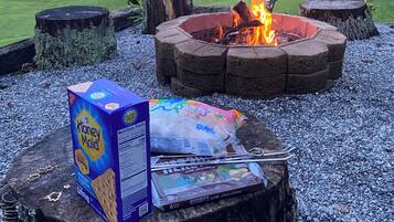 Un feu de camp, une boîte de céréales Honey Maid et une tablette de chocolat au lait Hershey's posées sur une souche d'arbre.