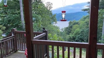 A wooden deck with a view of a lake and forested hills.