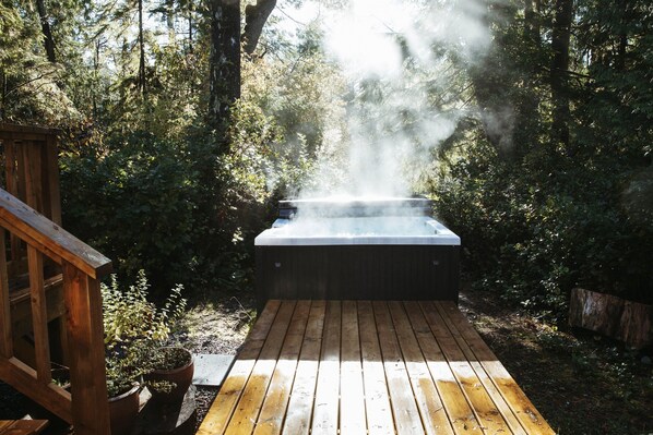 Un jacuzzi en un área boscosa con una terraza de madera.