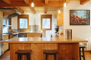 Una cocina con armarios de madera, una isla grande con taburetes y un cuadro en la pared.