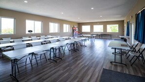 Una habitación amplia con varias mesas y sillas, ventanas grandes y un aro de baloncesto.