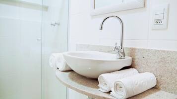 A bathroom with a white sink, a mirror, and a towel rack with towels.