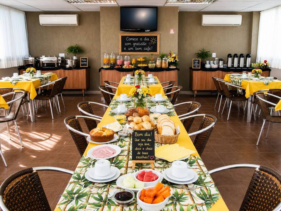 Uma mesa de buffet de café da manhã com mesas, cadeiras e diversos alimentos.