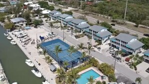 Luftaufnahme eines Küstenhotels mit Schwimmbad, mehreren Gebäuden und einem Yachthafen mit Booten.