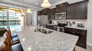 A modern kitchen with granite countertops, stainless steel appliances, and dark wooden cabinets. - Luxury Villa, Clubhouse, Pool, 15 mins from Disney (Kissimmee)