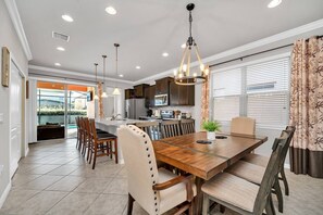 Una cocina moderna con armarios oscuros, una isla central y una zona de comedor con mesa y sillas de madera.