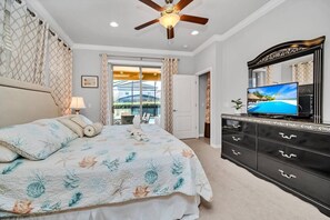 Quarto com uma cama, um ventilador de teto, uma televisão e uma cômoda.