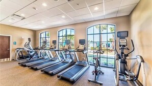 A gym with treadmills, elliptical machines, and stationary bikes, large windows, and a ceiling with recessed lighting. - Luxury Villa, Clubhouse, Pool, 15 mins from Disney (Kissimmee)