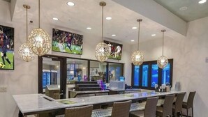 A modern kitchen with a large island, pendant lighting, and sports-themed wall art. - Luxury Villa, Clubhouse, Pool, 15 mins from Disney (Kissimmee)