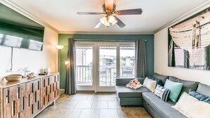 A modern living room with a grey sectional sofa, a wooden cabinet, and a ceiling fan.