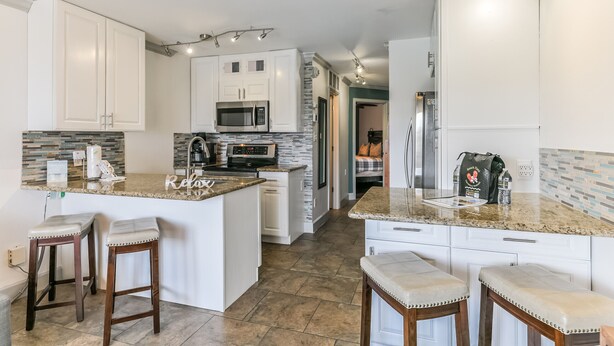 A modern kitchen with white cabinets, granite countertops, and a central island with bar stools.