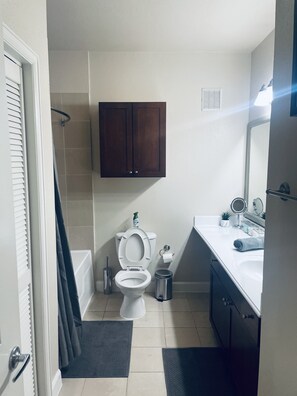Ein modernes Badezimmer mit Toilette, Waschbecken und dunklen Holzschränken.
