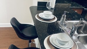 Un ripiano da cucina con un lavandino, un bicchiere da vino e una bottiglia di gel disinfettante.