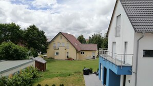 A residential area with a two-story house, a blue building with a balcony, and a well-maintained lawn.