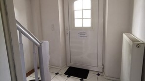A white door with a window, a black mat at the bottom, and a white radiator to the right.