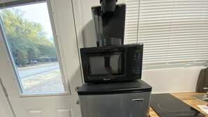 A compact kitchen with a refrigerator, a microwave, and a coffee maker on top.