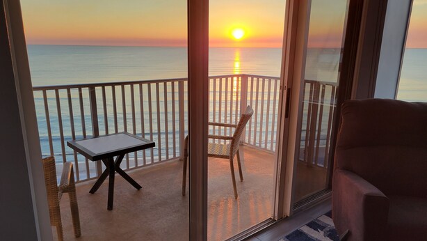 A balcony with a table and chairs, overlooking the sea during sunset. - BEAUTIFUL DIRECT GULF FRONT CONDO FORT MYERS BEACH 903B (Fort Myers Beach)