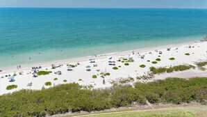 A beach with white sand, clear turquoise water, and several umbrellas. - BEAUTIFUL DIRECT GULF FRONT CONDO FORT MYERS BEACH 903B (Fort Myers Beach)