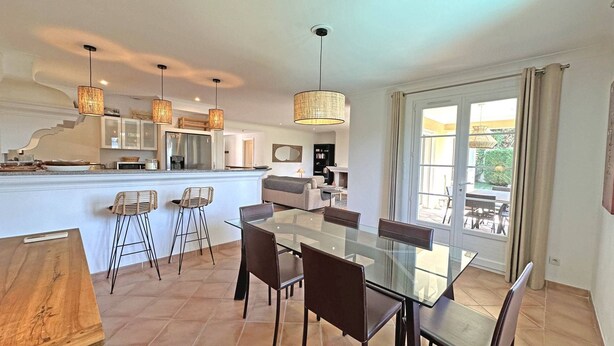 A modern kitchen with a central island, bar stools, and pendant lighting.