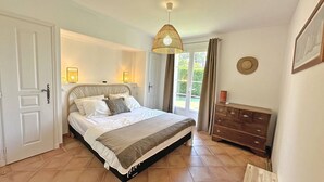 A bedroom with a bed, bedside lamps, a dresser, and a view of the outdoors.