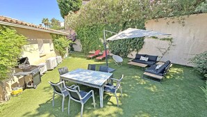 A patio with a table and chairs, a sofa, and a sun umbrella.
