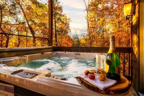 Een hottub met een houten terras, omringd door herfstbladeren.