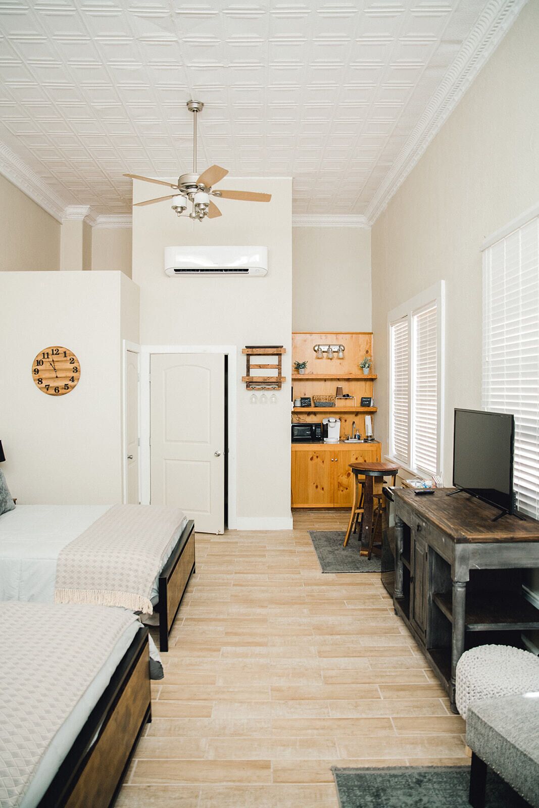 Un dormitorio con cama, ventilador de techo y un reloj de pared.