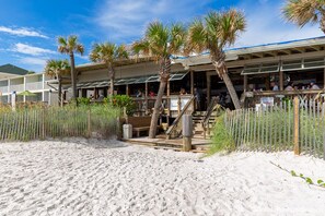 A beachfront hotel with outdoor seating, palm trees, and a sandy beach area. - Updated Townhome Blocks from the Beach! (Panama City Beach)